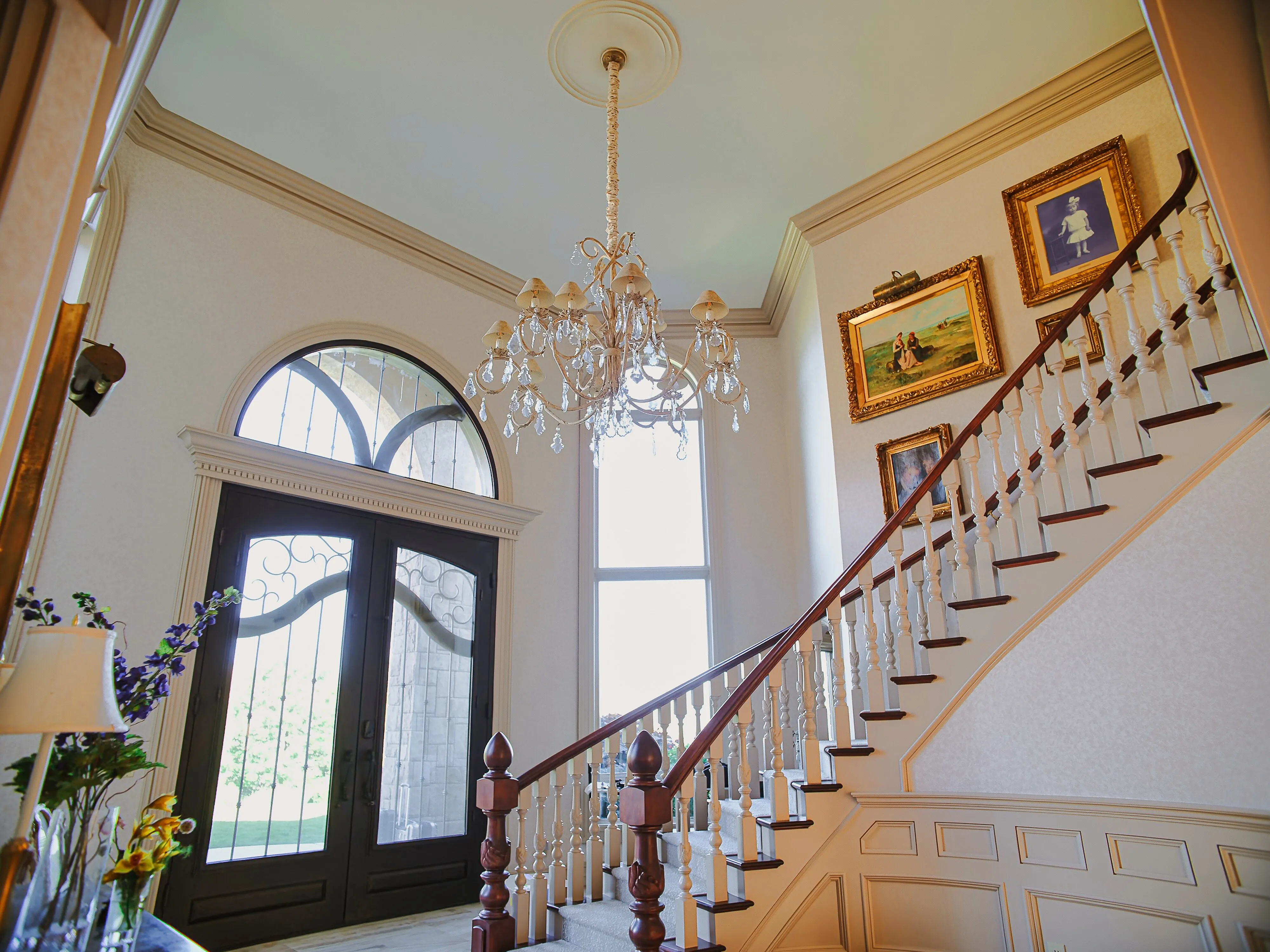 Two-story foyer with crystal chandelier and curved staircase