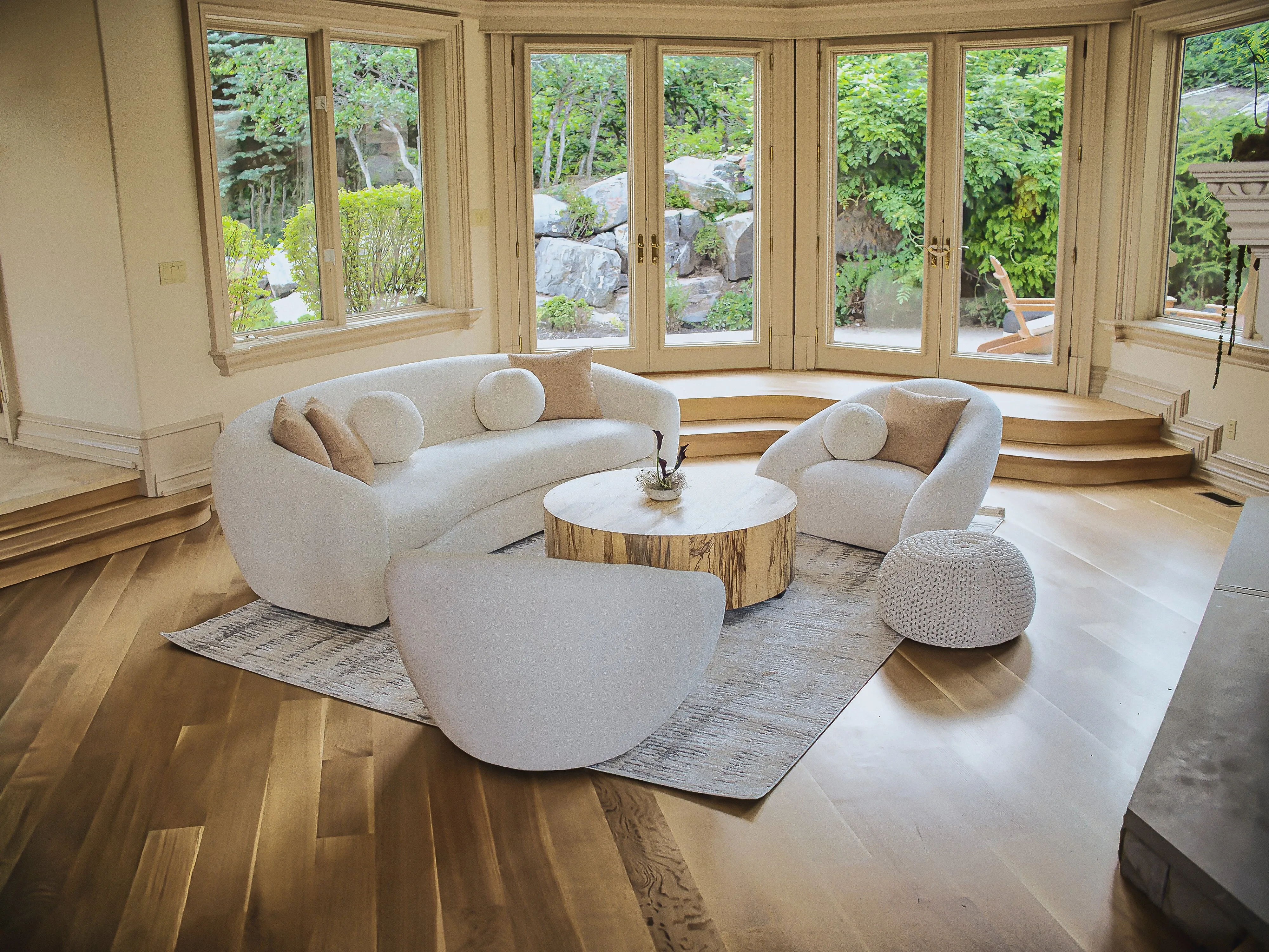 Family room with curved designer seating and walls of windows onto the garden
